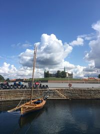 Sailboats moored at harbor against sky