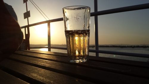 Close-up of beer in glass on table against sea and sky