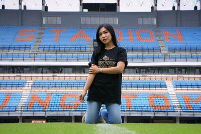 Portrait of young woman standing against building