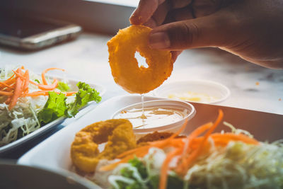 Cropped hand dipping food in bowl