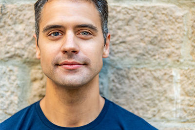 Close-up portrait of young man standing against wall