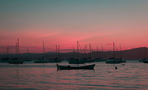 Sailboats moored in marina at sunset