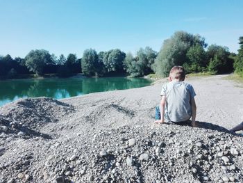 Full length of man sitting on shore against sky