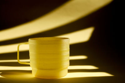 Close-up of yellow dirty  plastic cup with light and shadow as background