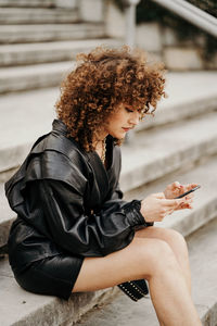 Side view of young woman using mobile phone