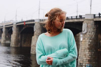 Young woman standing against bridge in city