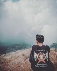 Rear view of man standing on land against sky