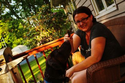 Tilt portrait of smiling woman with dog in back yard