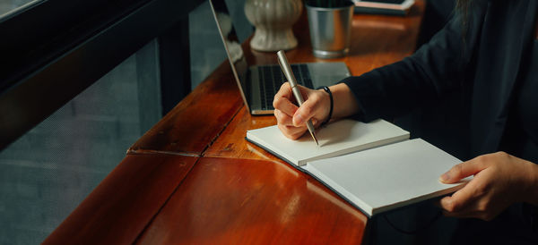 Midsection of man reading book on table