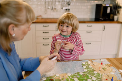 Happy grandson playing board game with grandmother at table