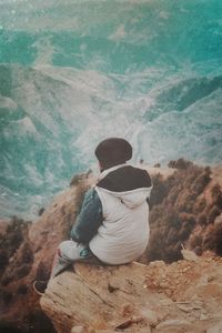 Rear view of woman sitting on rock