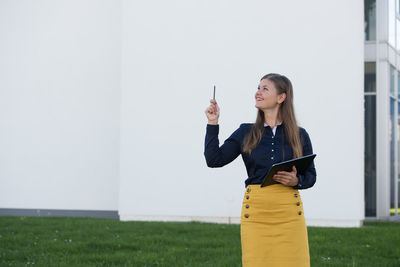 Full length of woman standing against yellow wall