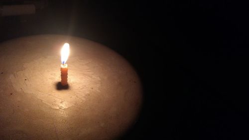 Close-up of lit candle in darkroom