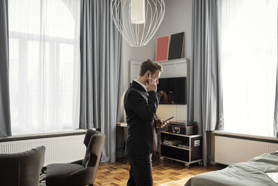 Side view of businessman talking on mobile phone while standing in hotel room