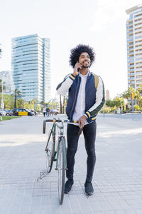 Casual businessman with bicycle on cell phone in the city, barcelona, spain