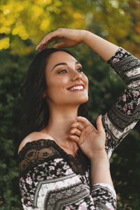 Close-up of smiling woman standing against trees