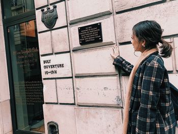 Woman standing by text on wall in city