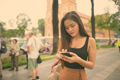 Young woman using mobile phone while standing outdoors