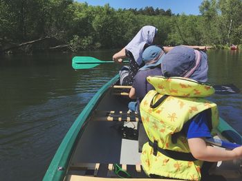 People on boat in lake against trees