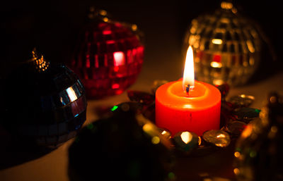 Close-up of lit candle amidst christmas ornaments on table