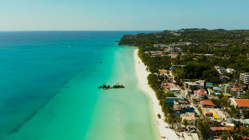 Tropical white beach with tourists and hotels near the blue sea, aerial view.