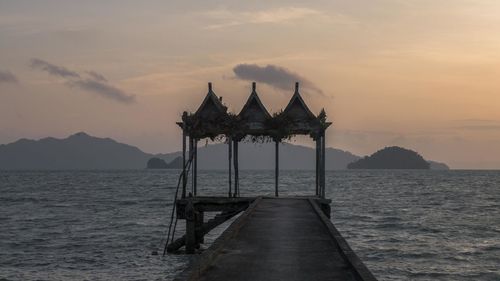 Pier on sea against sky during sunset