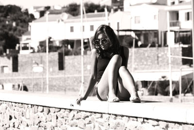 Woman sitting on wall in city