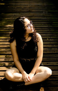 Beautiful young woman sitting with arms raised