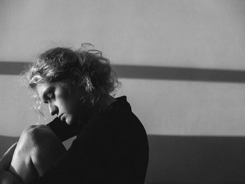 Side view of sad woman sitting against wall