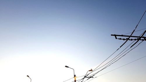 Low angle view of silhouette birds on cable against sky