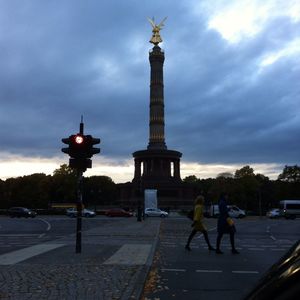 People in front of clock tower against cloudy sky