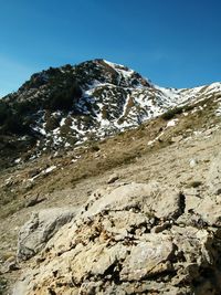 Low angle view of rocky mountains against clear blue sky