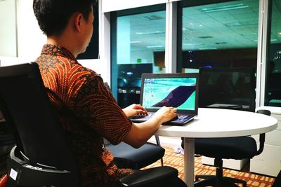 Young woman using mobile phone while sitting on chair