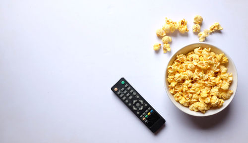 Copy space delicious popcorn in a bowl with tv remotes on a white background