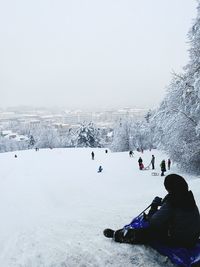 People skiing on snow covered mountain against clear sky