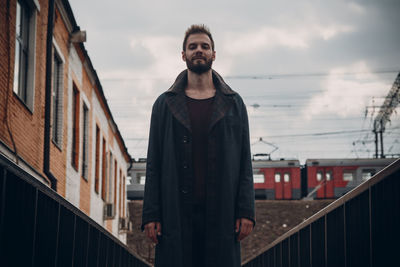 Man standing by railing in city against sky