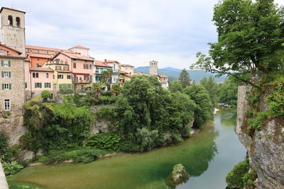 Scenic view of river by buildings against sky