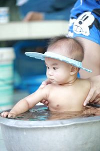 Midsection of mother bathing son in tub outdoors