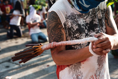 Midsection of man holding rope while standing outdoors during traditional festival