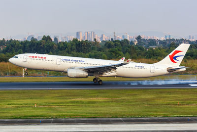 Airplane flying over airport runway against sky