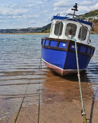 Boat moored on lake against sky