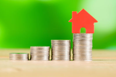 Close-up of stacked coins with model house on table