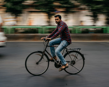 Side view of young man riding bicycle on street