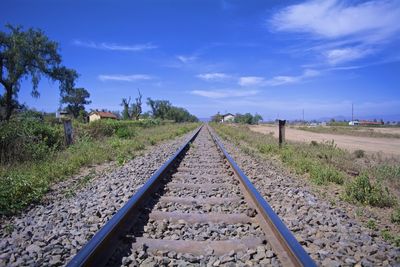 Railroad tracks amidst trees against blue sky