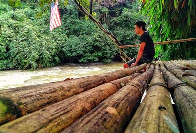 Man sitting on log in forest