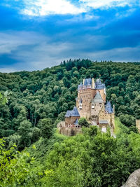 Castle on hill against cloudy sky