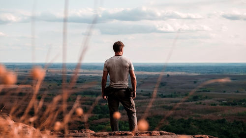 Rear view of man standing on land against sky