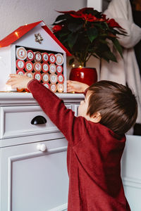 Rear view of boy playing with mobile phone at home