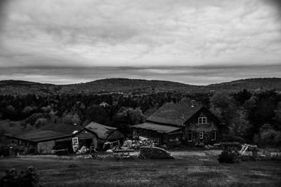 Houses on field against cloudy sky