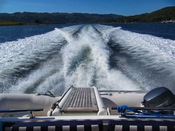 Waves splashing on boat in sea against sky